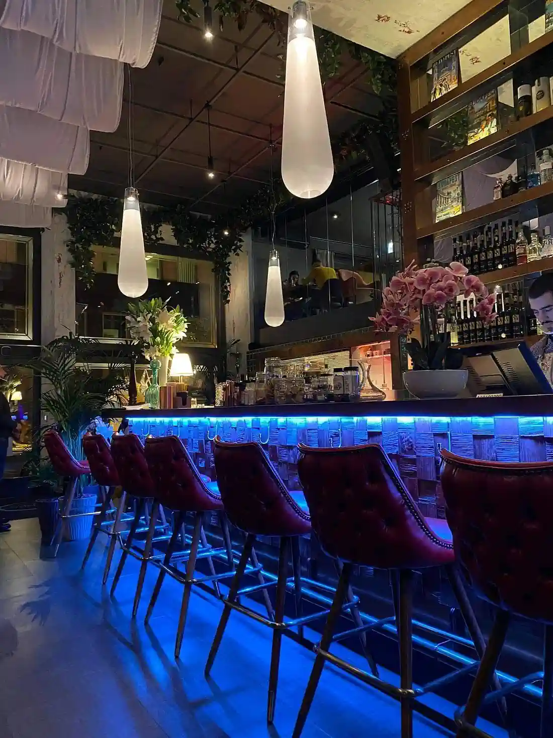 Image of the red leather bar stools and the blue backlight of the bar